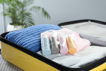Fototapeta na wymiar Plastic bag of cosmetic travel kit in suitcase indoors