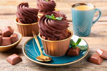Delicious cupcakes with mint and chocolate pieces on wooden table, closeup