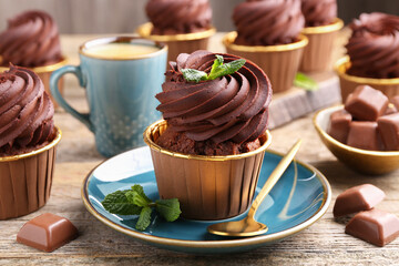 Delicious cupcakes with mint and chocolate pieces on wooden table, closeup