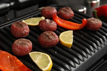 Electric grill with meat balls, bell pepper and lemon on table, closeup