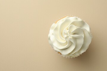 Tasty vanilla cupcake with cream on beige background, top view. Space for text