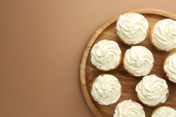 Tasty vanilla cupcakes with cream on dark beige background, top view. Space for text