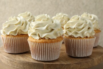 Tasty vanilla cupcakes with cream on table, closeup