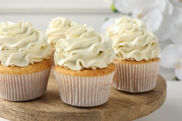 Tasty vanilla cupcakes with cream on white table, closeup