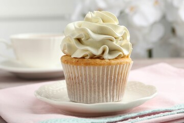 Tasty cupcake with vanilla cream on table, closeup