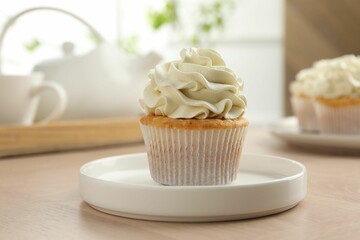 Tasty cupcake with vanilla cream on light wooden table, closeup