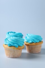 Delicious cupcakes with bright cream on light background, space for text