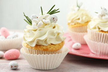 Tasty Easter cupcakes with vanilla cream on wooden table