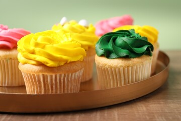 Delicious cupcakes with bright cream on wooden table, closeup