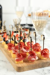 Different tasty canapes on white marble table, closeup