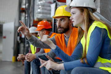 Successful workers, engineers wearing hard hats and work wear, pointing fingers at something