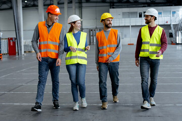 Successful employees, managers wearing hard hats, work wear and vests talking, discussing work