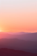 Fototapeta premium Vibrant Sunrise Over Mountains. Warm-toned sunrise over a tranquil mountain range, ideal for travel or nature themes.