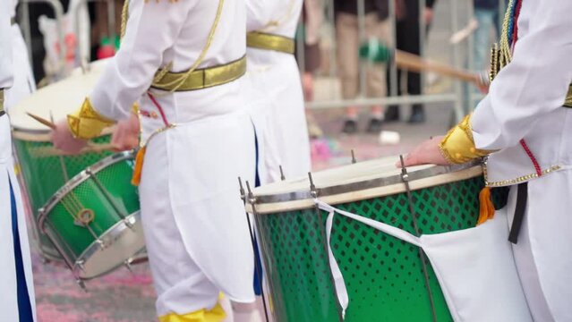 Group of drummers playing rhythmic sambo music during a carnival procession closeup dressed in colorful traditional suits.