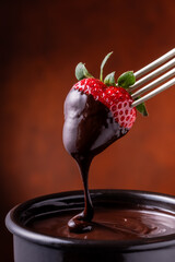 Dark chocolate fondue with strawberries in the foreground - 786293814