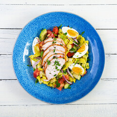 Healthy chicken salad. Fresh salad with avocado, tomato, chicken and herbs. Top view