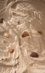 Beach sand with marine stones under the water texture shadows close up