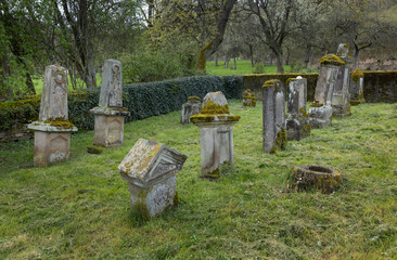Tombstones at historical and abandoned Jewish cemetry at Lösnich Graveyard with gate with...