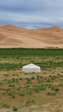 Aerial around view on lonely yurt near the sand dunes in the Gobi Desert, Mongolia. Vertical video