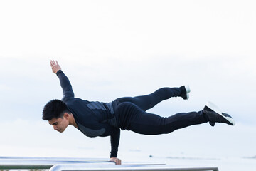 Athletic asian man practicing intense exercise in bars at calisthenics gym outdoors