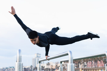 Athletic asian man practicing intense exercise in bars at calisthenics gym outdoors