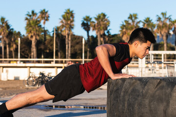 Young sportsman training outdoors, doing push ups