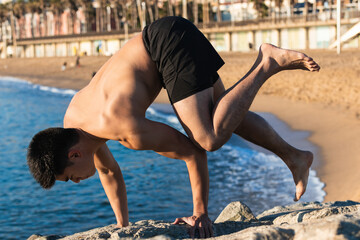 Young man doing yoga on the beach