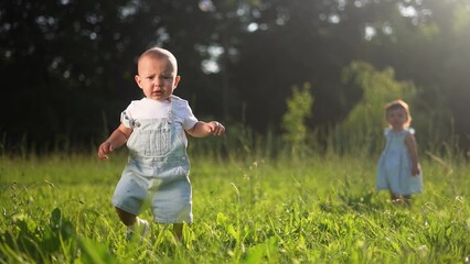 baby first steps. baby son a takes hesitant first steps in nature park falls learns to walk. happy...