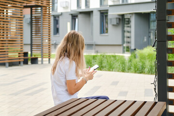 Unrecognizable woman in sunglasses on bench with smartphone