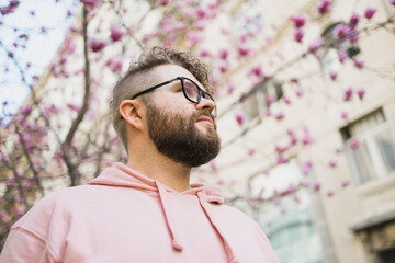 Spring fashion style. Male sexuality. Bearded man portrait on blooming flower tree background....