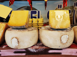 Delicious yellow cheese, cut into chunks, on the shop window