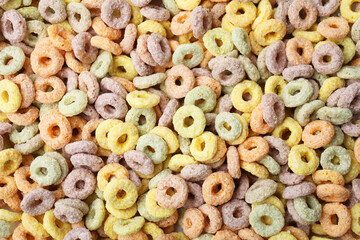 Tasty cereal rings as background, top view