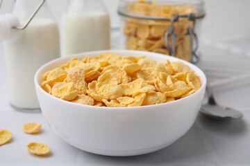 Tasty crispy corn flakes in bowl on white table, closeup. Breakfast cereal