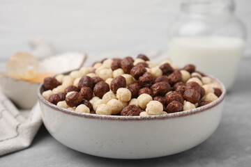 Tasty cereal balls in bowl on grey table, closeup