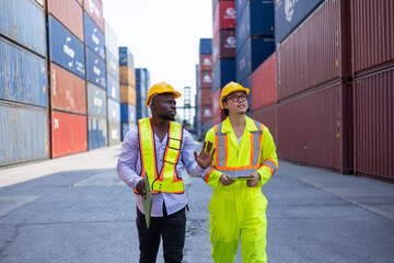 Asian and black engineers check cargo at shipping container