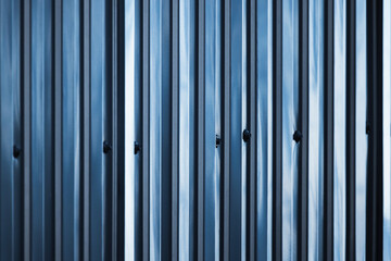 Shiny blue ridged metal fence connected with bolts and nuts, close up