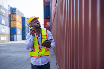 Black engineer in warehouse inspecting goods at industrial container yard