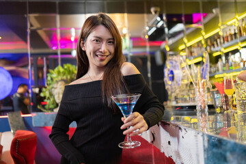 Confident Woman with Blue Cocktail at Stylish Bar