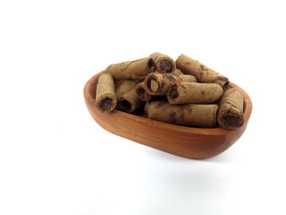 Chocolate wafers rolled in a wooden bowl isolated on white background. A delicious snack that tastes sweet and crunchy.