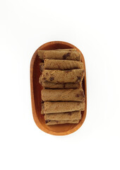Chocolate wafers rolled in a wooden bowl isolated on white background. A delicious snack that tastes sweet and crunchy.