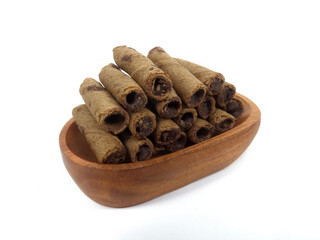 Chocolate wafers rolled in a wooden bowl isolated on white background. A delicious snack that tastes sweet and crunchy.