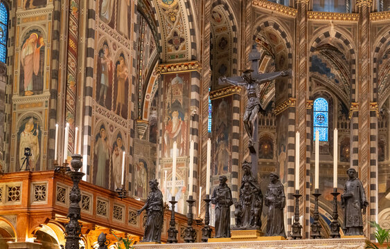 View of decorative metal statues of saints and crucifix decorating the interior of gothic cathedral in Italy