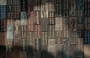 Chinese lettering teachings and Carved buddha images into a slab of colored tiles on temple wall of...