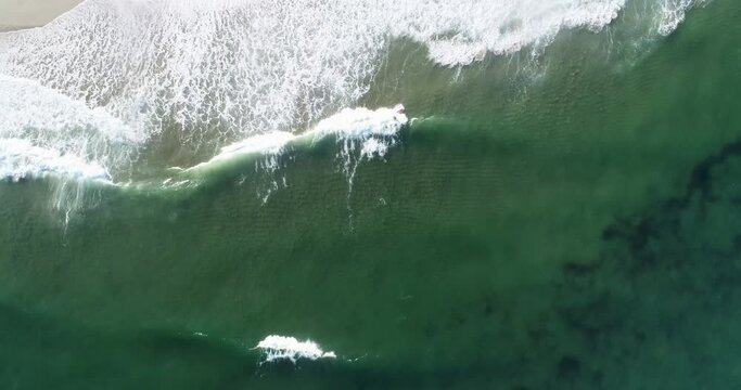 aerial drone video of a surfer surfing a wave with a red surfboard. Overhead view
