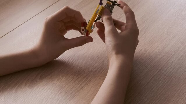 boy created and manipulates with transformer robot, child plays with colored plastic parts constructor, creates equipment, development creativity, fine motor skills