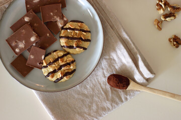 Cup of tea or coffee, cookies, macaroons, chocolate, various nuts and cocoa powder on white background. Top view.