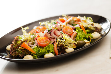 Fresh  Vegetable green salad with sauce on a black plate