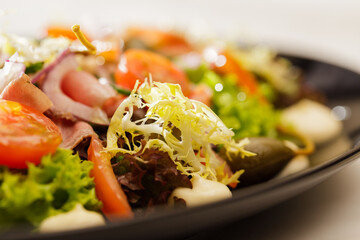 Fresh  Vegetable green salad with sauce on a black plate