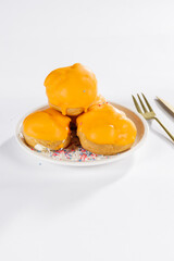 Oranje Mini Soesjes cakes for Kings Day on a white plate with gold cutlery