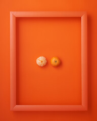 Clementines in picture frame on orange background